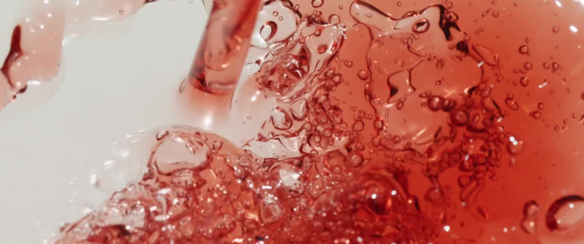 Red liquid with bubbles being stirred on a white surface