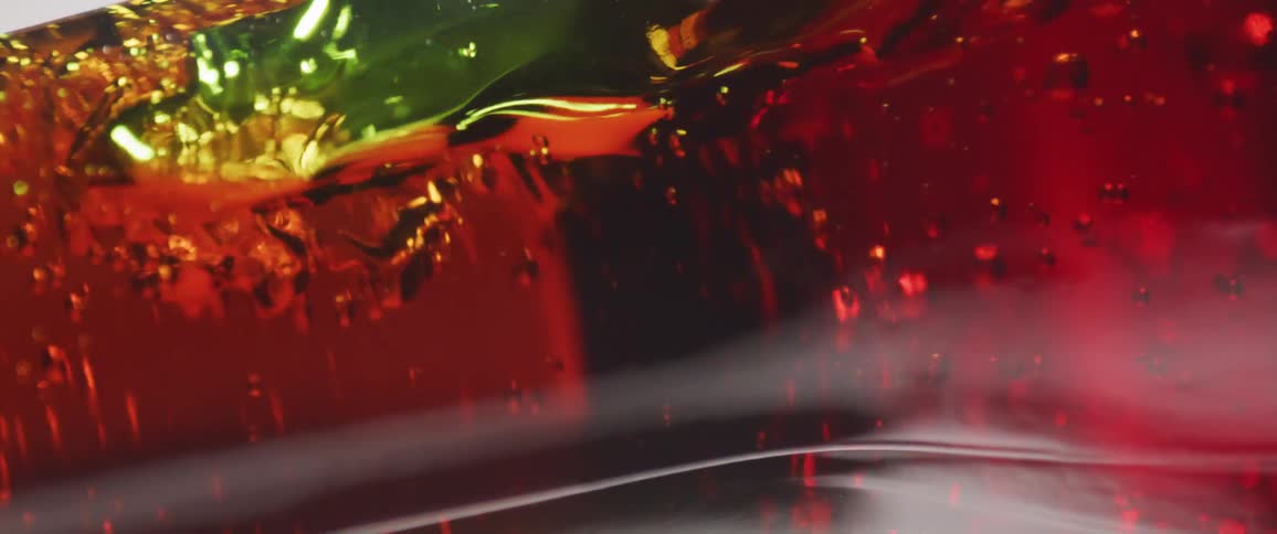 Close up of a shaken red drink in a green glass bottle