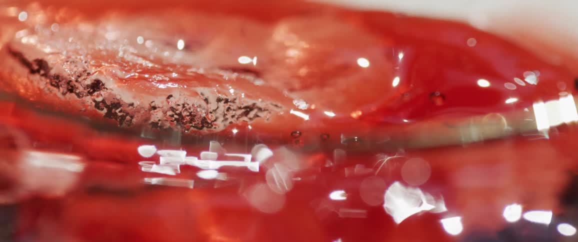 Ice lands in a glass of red liquid