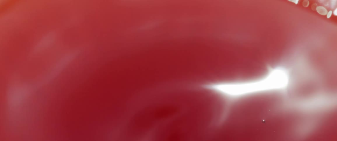 A red liquid is swirling as it reflects light