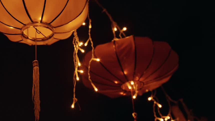 Close up of festive lights and decorations hanging from a line outdoors at night
