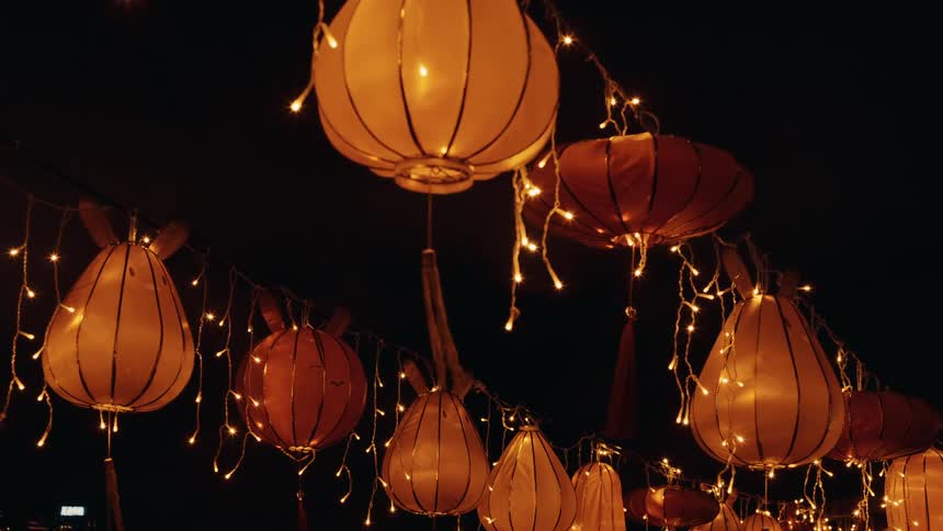 Orange lanterns lit by festive lights at night
