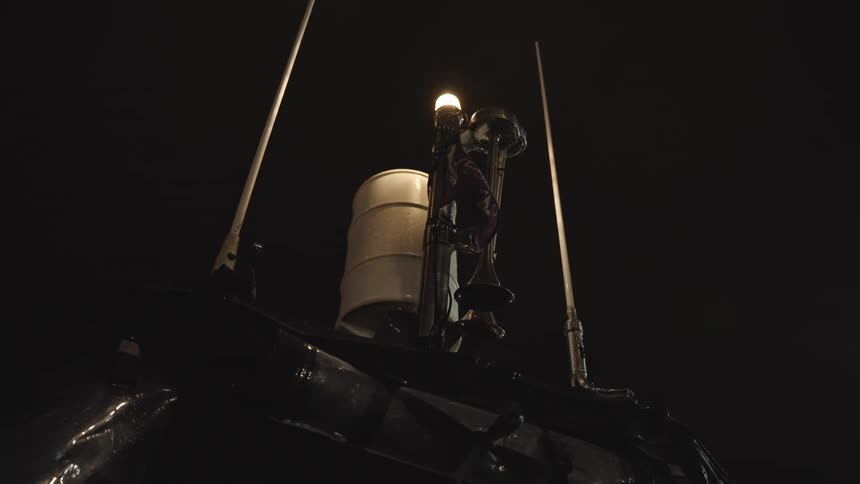 Lit fixture highlights vertical metal structure with antennas under night sky