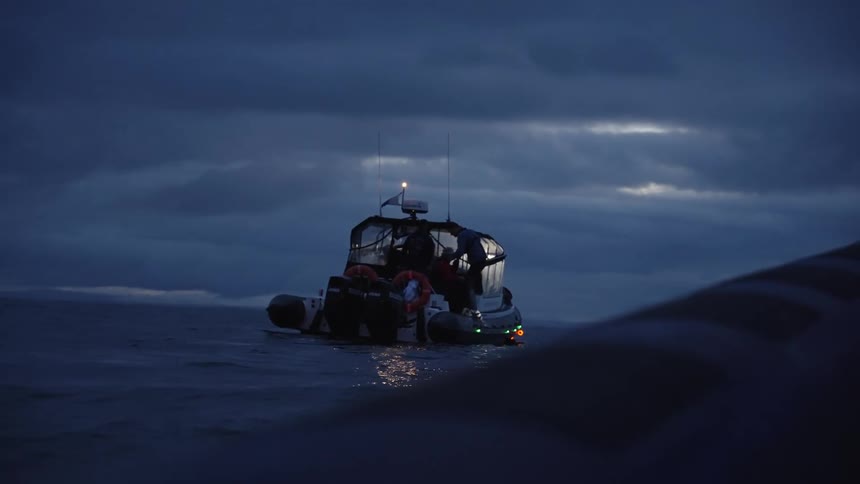 Illuminated boat sailing on calm sea at dusk