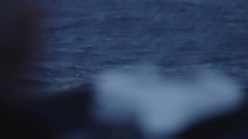 The man swims from the boat with lights on his back