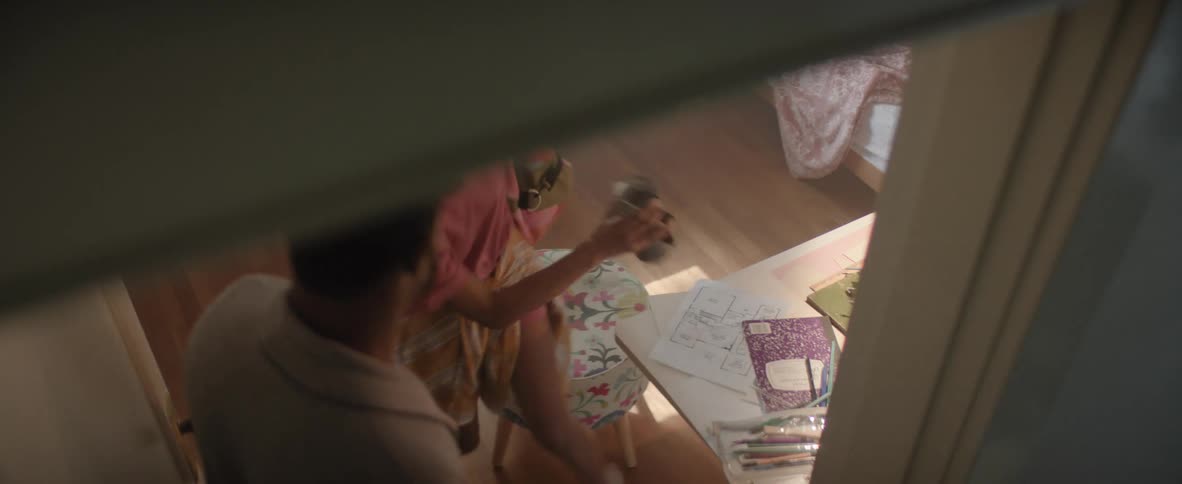 Man wakes his daughter asleep at the table surrounded by notebooks and colored pencils