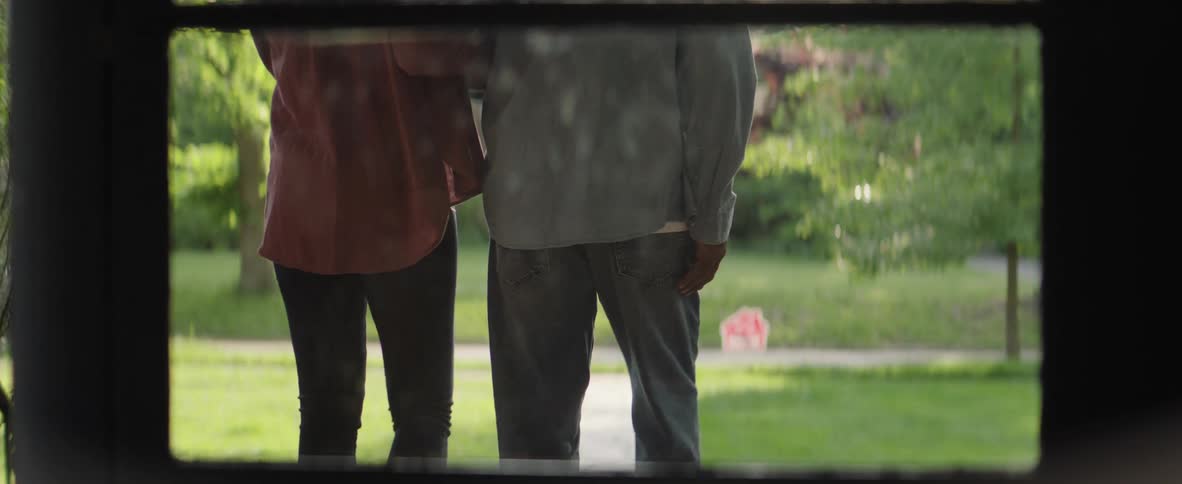 A couple walk out of a house walking arm in arm towards the street