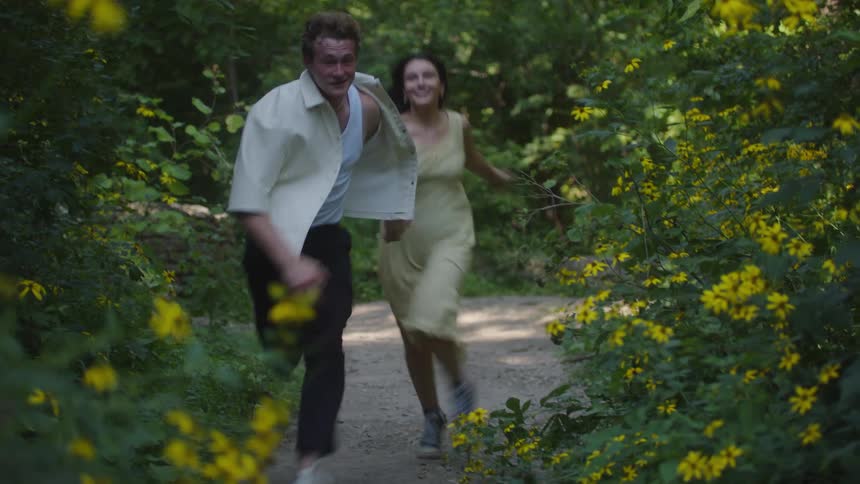 Couple running happily along a trail surrounded by yellow flowers