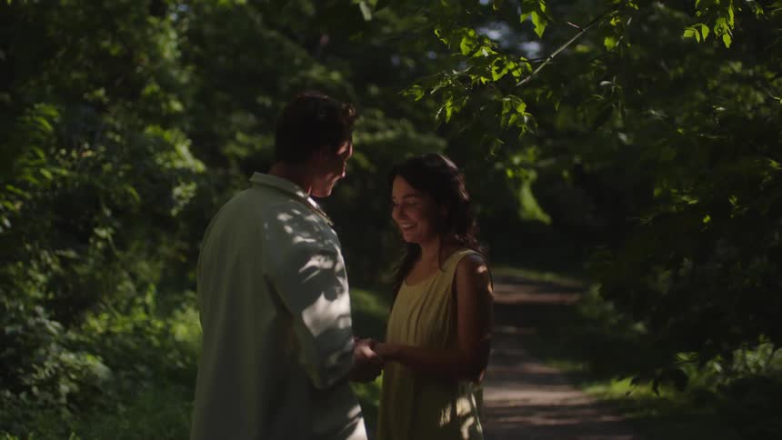 A couple shares a romantic moment in a sunlit forest