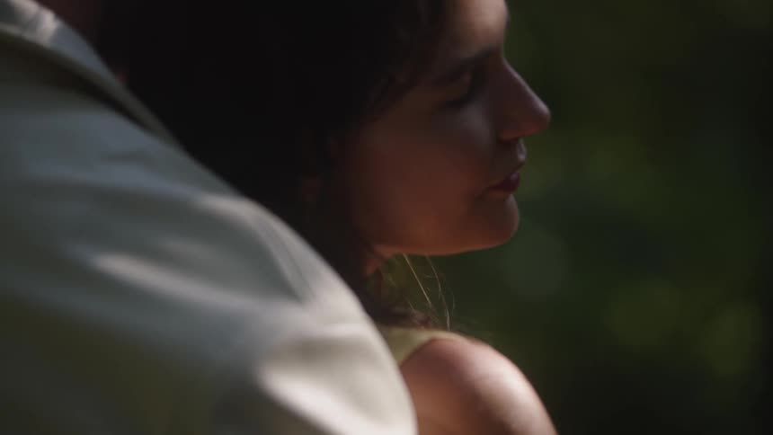 Woman smiles while being back hugged by a man outdoors