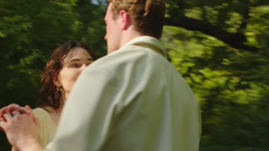 Couple standing on a path in the woods slow dances on a sunny summer day
