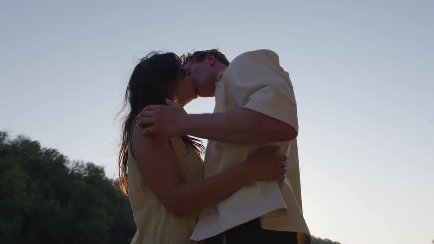 A young couple kissing while standing together outdoors during daytime