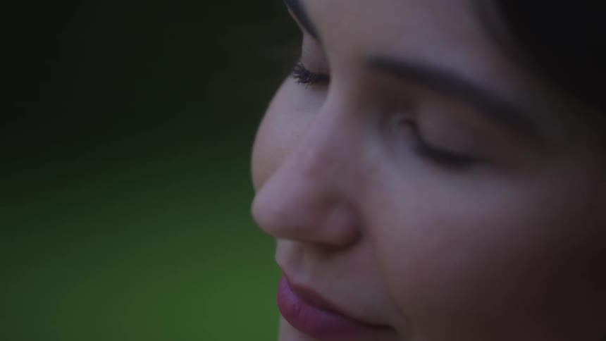 Woman smiles while glancing upward as she stands outdoors