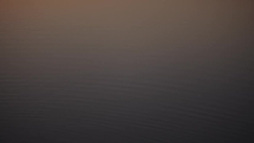 Calm water surface reflects the soft hues of dusk