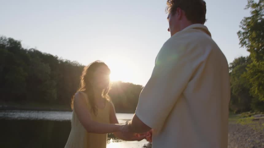Couple near the water stops slow dancing and turns to walk