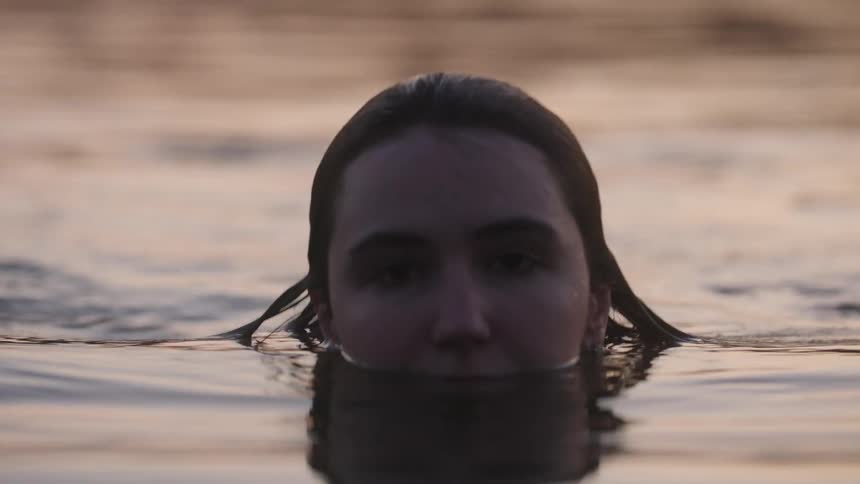 Closeup of young beautiful woman in water at dusk