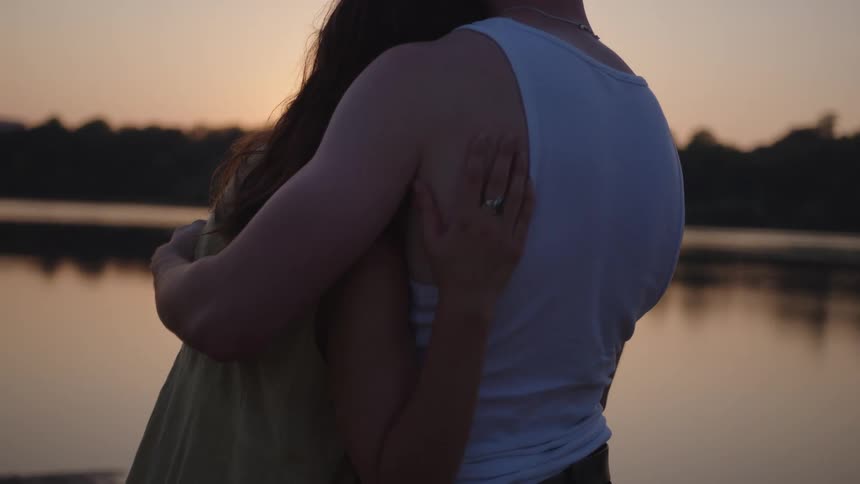 Couple embraces by the lake at sunset