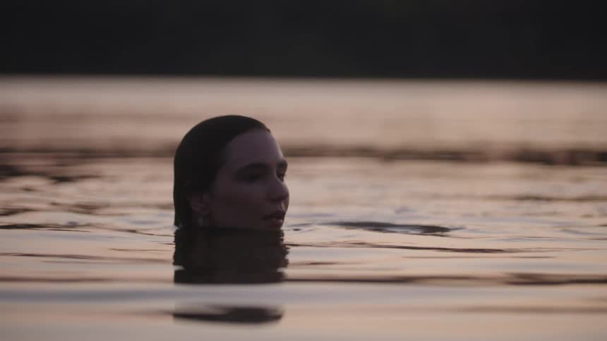 Woman swimming alone near dusk creates ripples