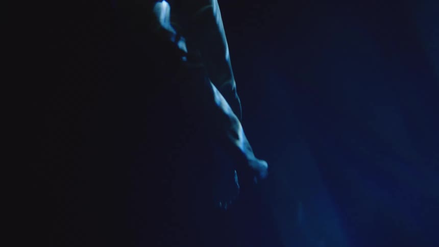 Leg extended submerged in bluish water under soft light