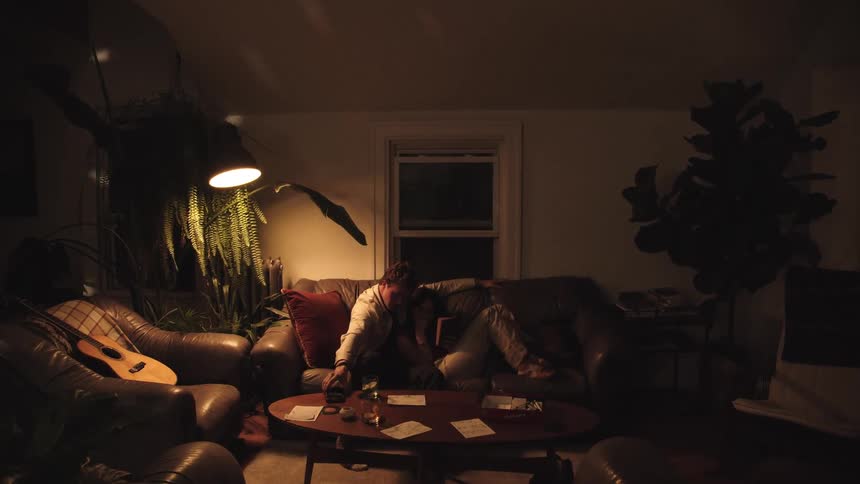 Couple relaxes embraced on the couch under warm light in a cozy living room