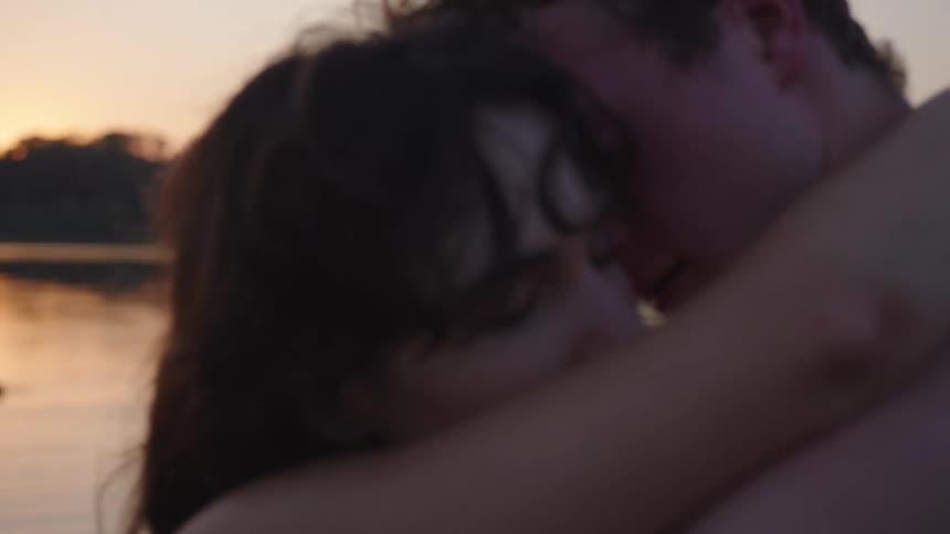 A couple shares a tender embrace at dusk by the water