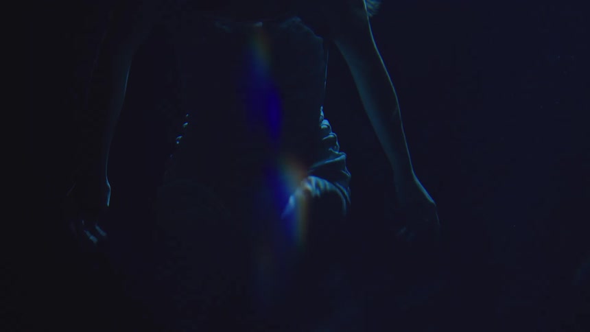 A female swims underwater at night with only her body visable