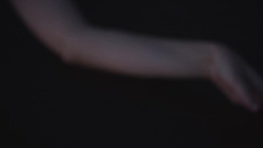 Hand gently touches the dark surface of the water