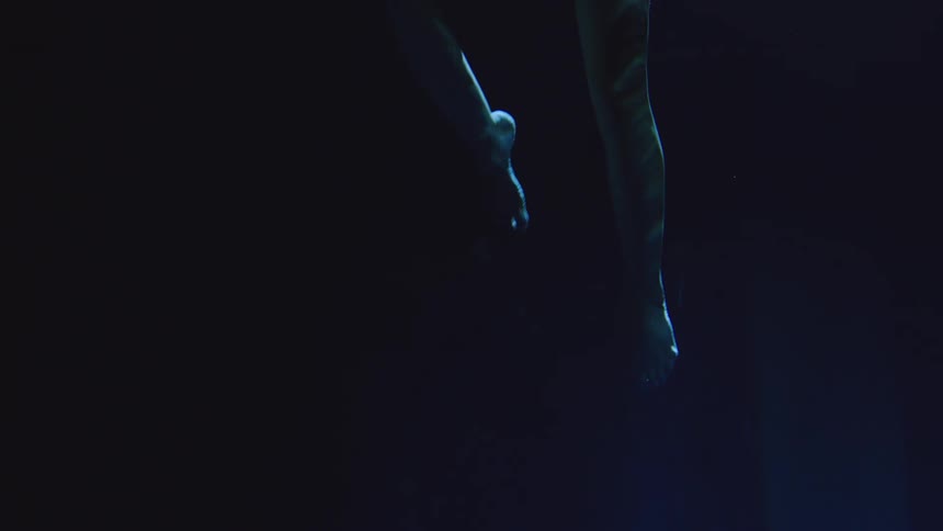 A pair of legs swimming downward in water