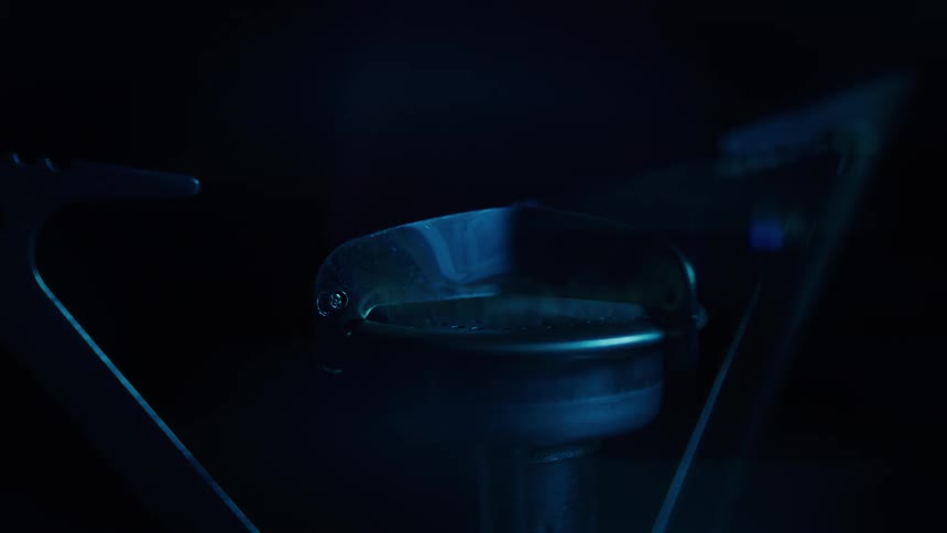Blue flame softly illuminates a burner in a dark setting