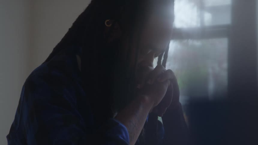 Man bows his head with clasped hands in a moment of prayer