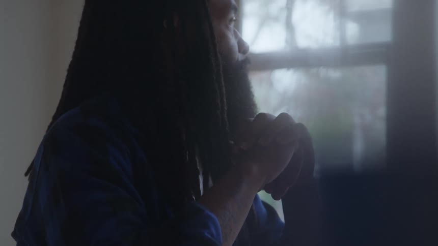 Man gazes out the window with his hands resting under his chin