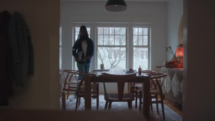 Person stands up from the dining table in a room lit by natural light