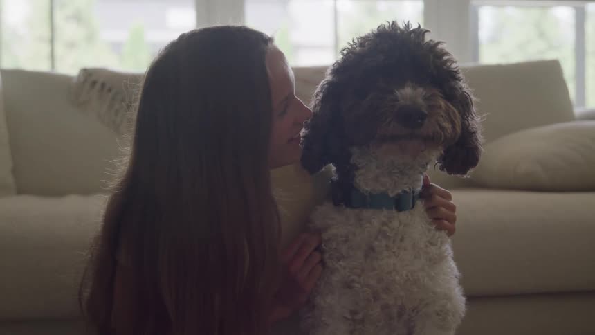 A woman affectionately pets a dog in a bright living room