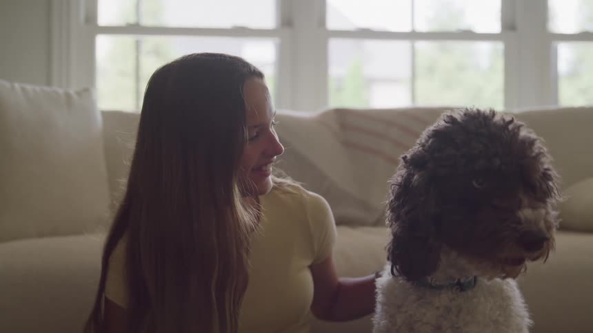 Woman sitting on the floor gazes affectionately at a dog indoors