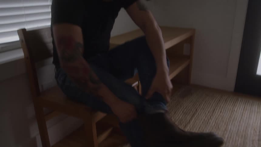 Man puts on his shoes puts on his jacket and walks out the door