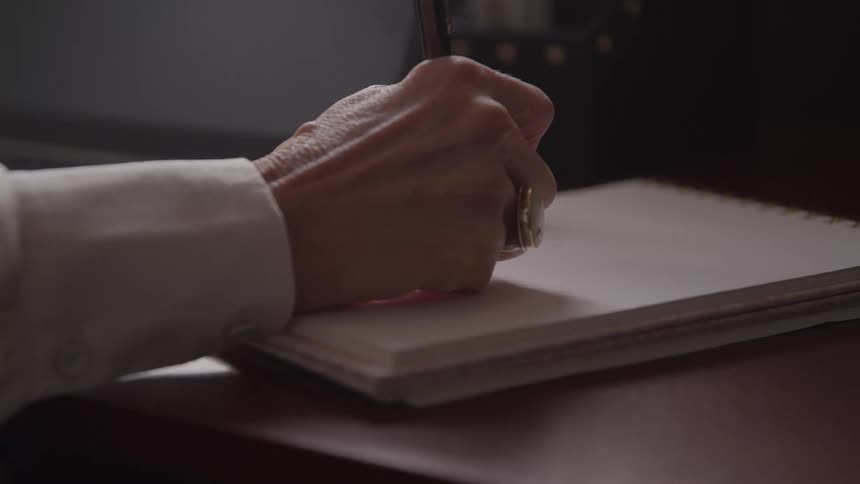 The woman is writing with a pen on a pad