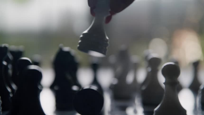 White piece is moved across chessboard in strategic moment with blurred background
