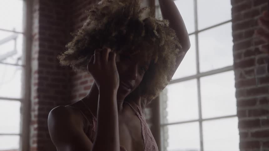 Woman touching her hair while moving in a room lit by natural light
