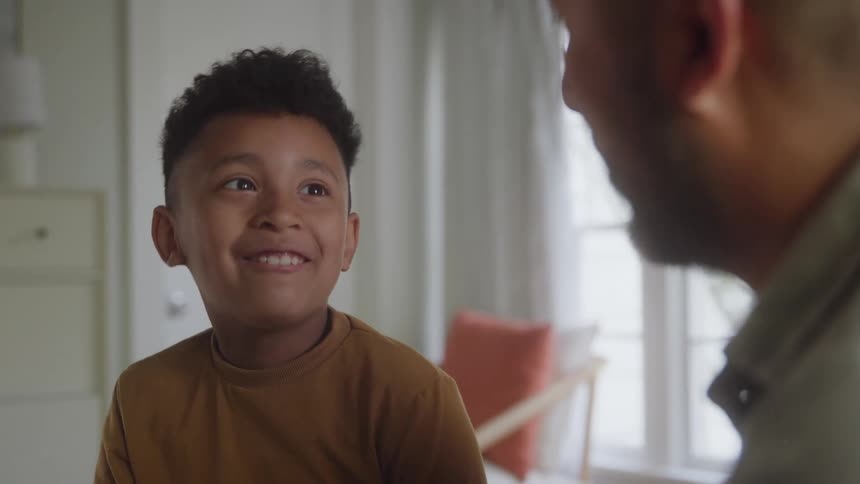 A boy smiling and talking with an adult man