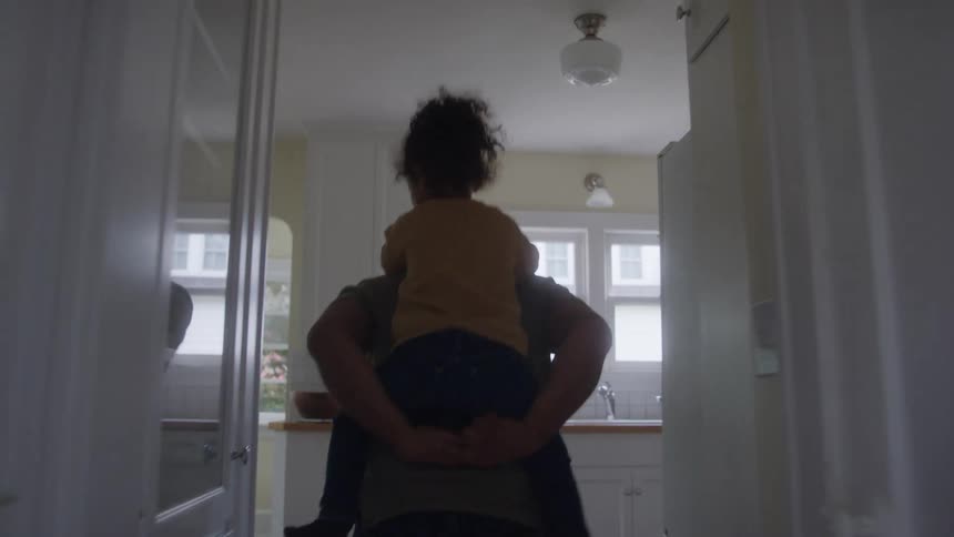 Father carrying his daughter in his arms inside the house