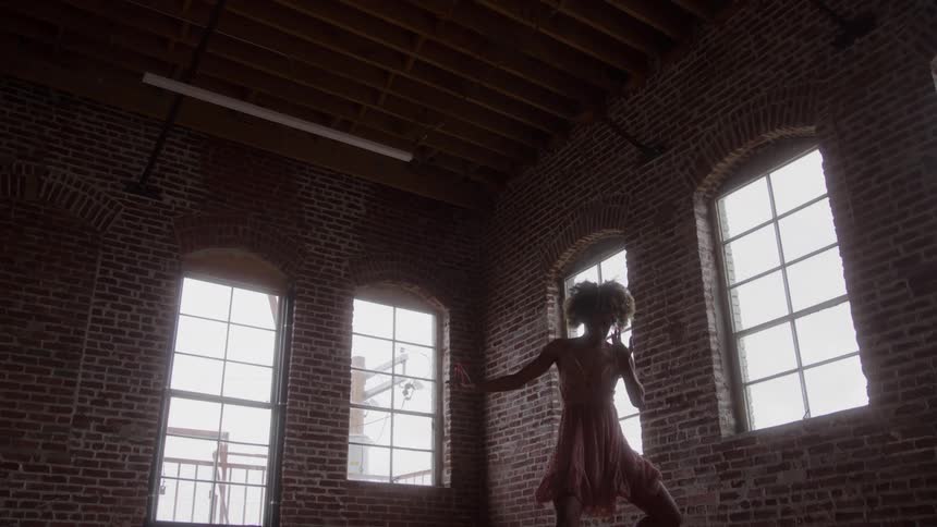 The woman twists and waves her arms while dancing