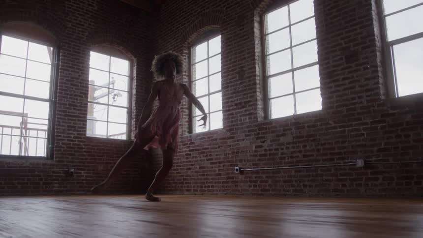 A black female ballet dancer dancing in an empty room during daytime