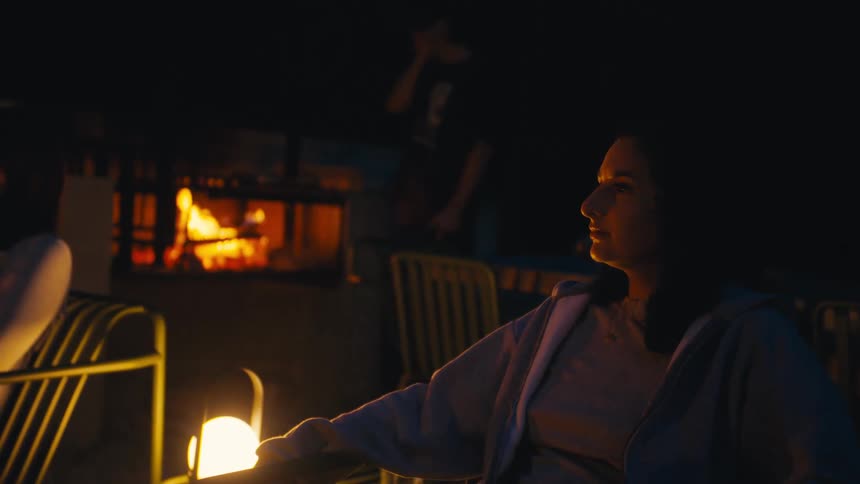 Woman sitting by the fire on an outdoor night
