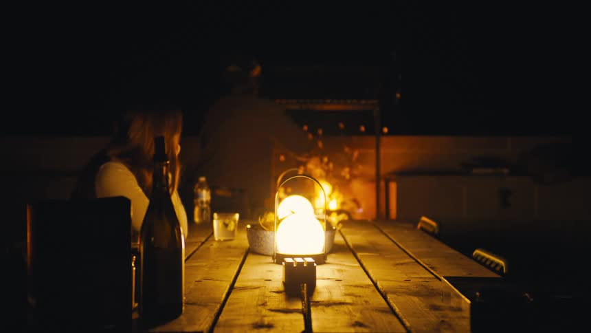 Woman sitting at a lanternlit table at night