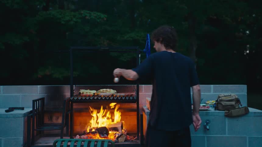 Outdoor grilling of food on concrete structure during gathering in wooded area