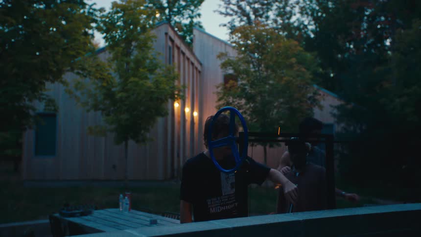 Three men in a backyard with one of them grilling meat on a barbecue