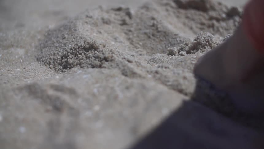 Person moves their foot in sand