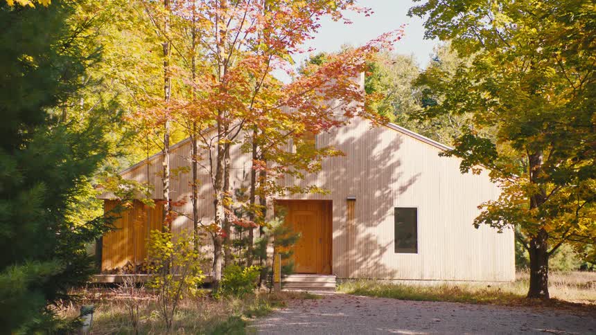 Wooden house surrounded by trees with yellowing leaves in early autumn
