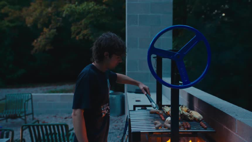 The man is grilling food in his yard