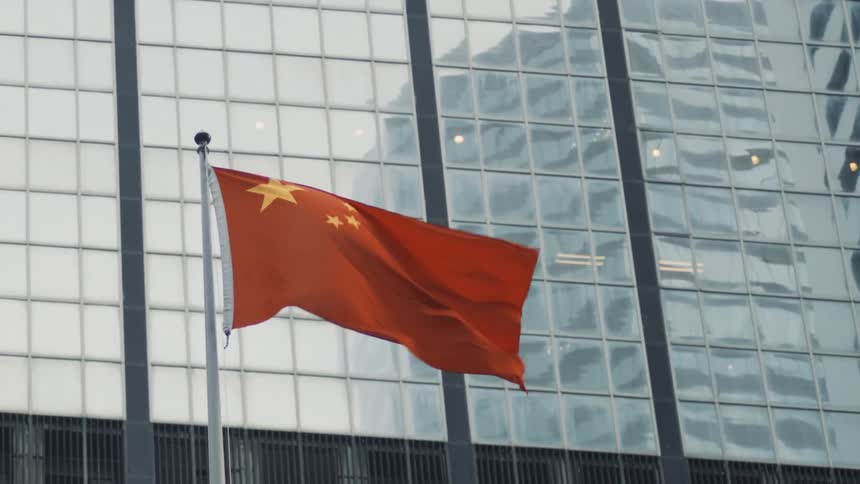 Chinese flag fluttering in the wind in front of a sky scraper